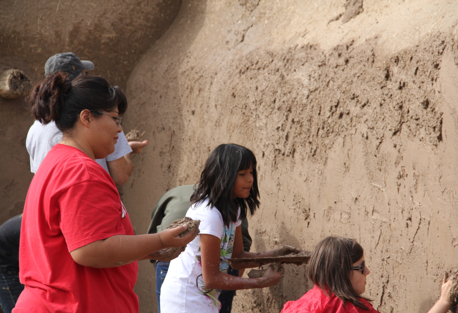 Families plastering a wall with mud