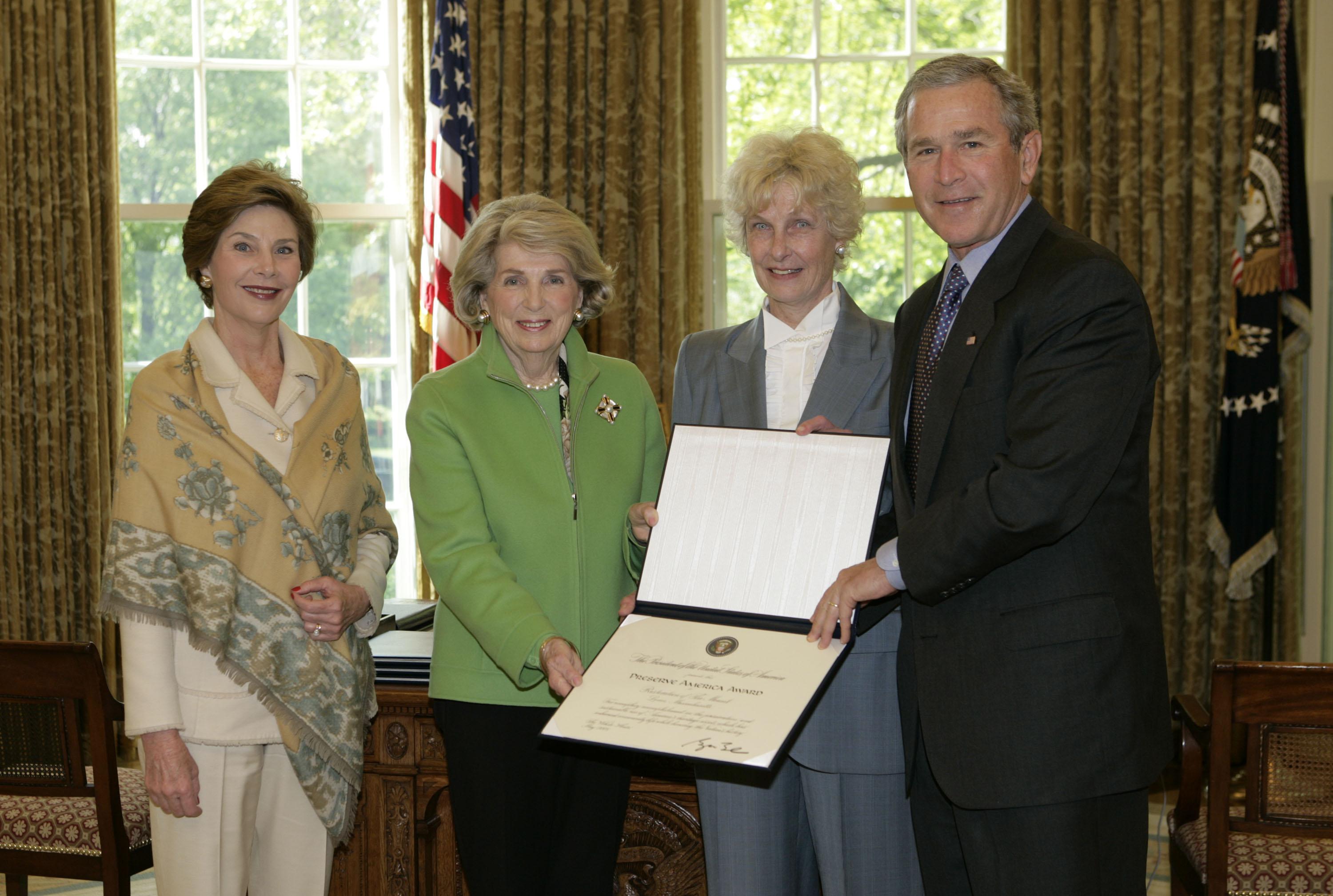 President George W. Bush and Laura Bush present the 2005 Preserve America Presidential Award to members of the Edith Wharton Restoration in the Oval Office Monday, May 2, 2005. They are, from left, Barbara de Marneffe, Co-Chairman, Board of Trustees of Cambridge, Massachusetts, and Stephanie Copeland, President and CEO, of Stockbridge, Massachusetts. (White House photo by Eric Draper)