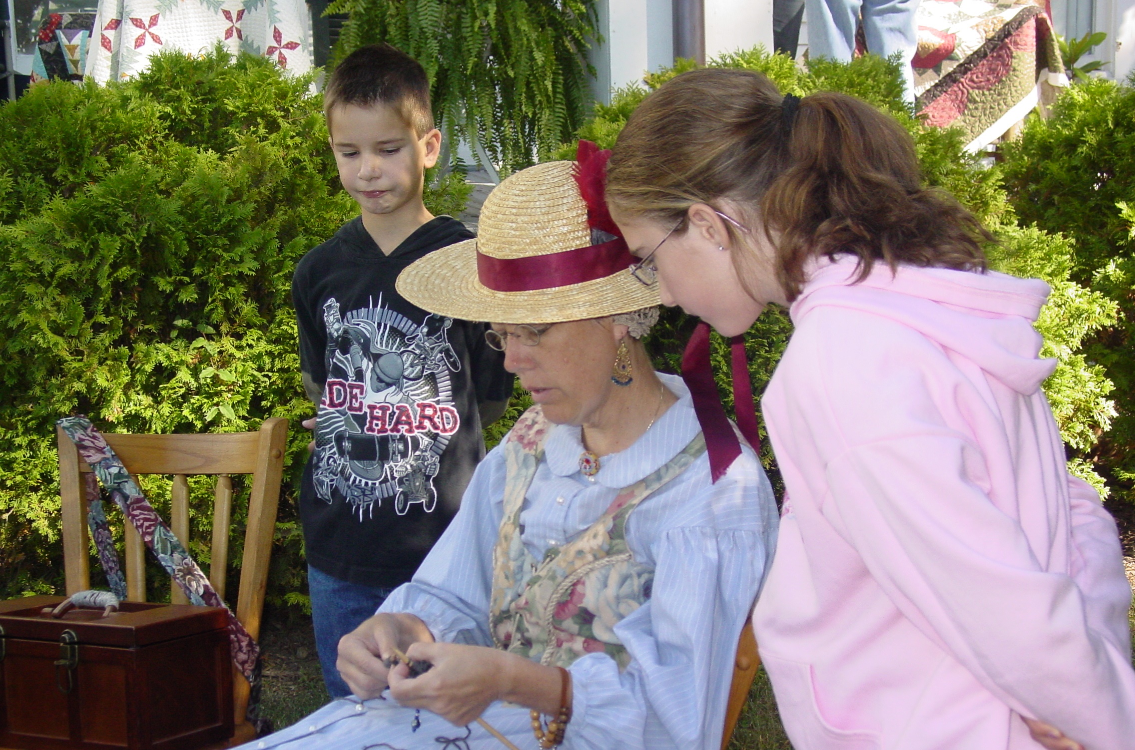 Children watch a woman in period costume demonstrate knitting during Down Home Days, a heritage festival celebrated each spring in downtown Chickamauga