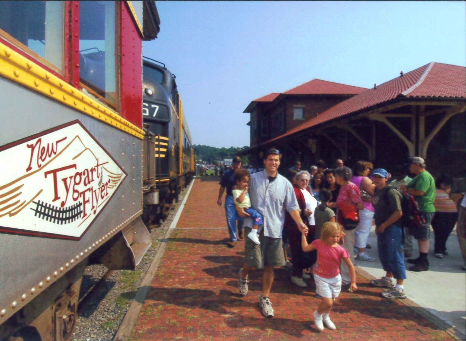 A tourist excursion train with passengers disembarking beside the historic Elkins depot.
